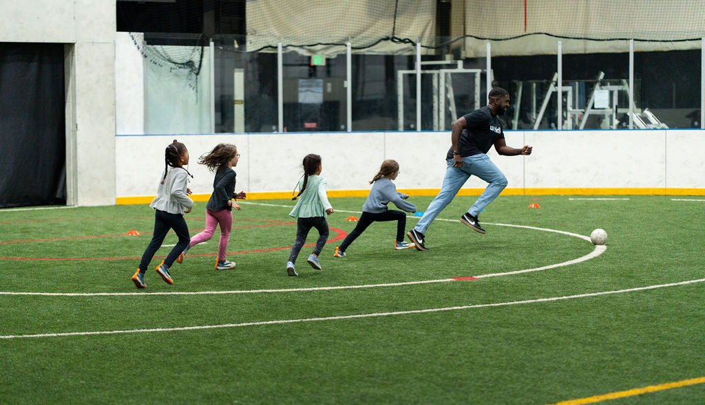 kids chasing a soccer ball on an indoor field